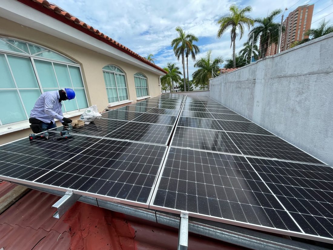 Técnico instalando paneles solares monocristalinos sobre cubierta metálica con perfilería de aluminio